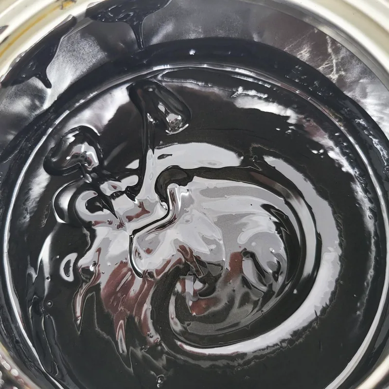The swirled surface of black open-gear grease in an open pail.
